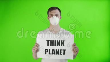 年轻的激进分子，脸上戴着面具，并在色度关键背景上张贴“思考星球”海报